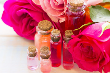 Spa and wellness setting with rose flower, sea salt, oil in a bottle on wooden white background