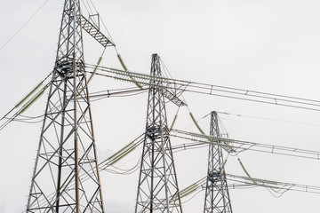 power electric transmission lines with wires insulators and wires at electrical substation with transformers covered with snow in winter