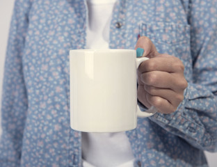 Hand holding white ceramic coffee cup. mockup for creative design branding.