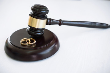 Close up of Judge gavel deciding on marriage divorce and two golden marriage ring