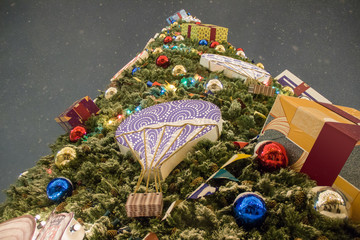 Giant christmas tree decorated with colorful balls,garland and presents during snowfall