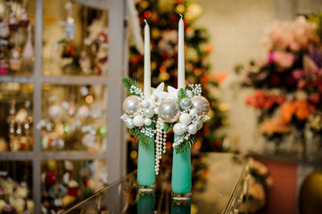 Two decorative Christmas candles decorated with fir branches, beads and little glass balls
