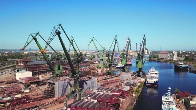 Drone flying forward to cranes in the shipyard