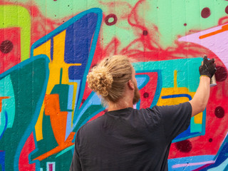 young man use his talent and feeling for art to apply this with various colors to a city wall