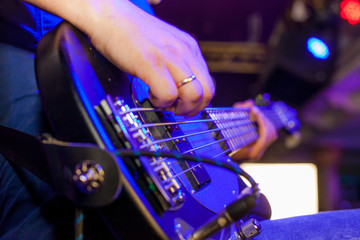 Fototapeta na wymiar Musician plays bass guitar on stage in neon light