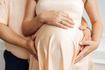 hands and belly of the future mother and father