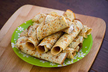 Pancakes rolls with cottage cheese on a wooden board. Pancakes with cheese. Shrovetide.