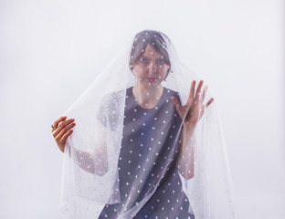 Portrait of young woman under white veil. Feelings, excitement, privacy, isolation concept.