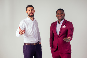 Two multinational young businessmen hand shaking hands in the studio on a white background