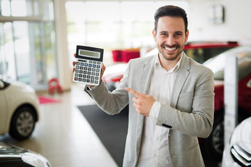 Man holding a calculator in the car showroom, good price