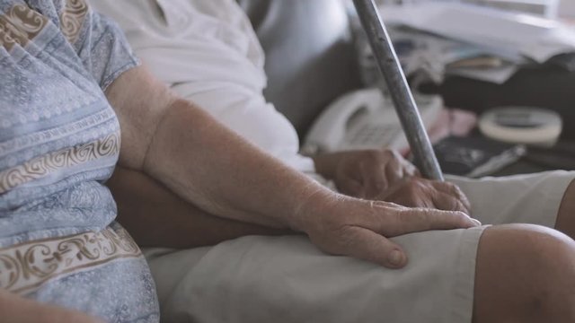 cinematic shot of an elderly couple sitting on a sofa holding hands