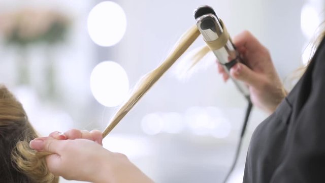 Hairdresser salon, master make hairstyle with curling iron, close up