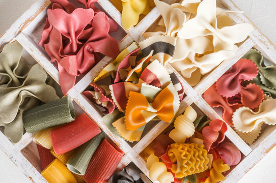 Mixed set of dry multi-colored Italian pasta on a white old wooden box. Background. Close up.