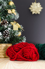 Vertical. Christmas tree and skeins of yarn on the wooden table on a black background