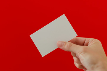 Right woman's hand holding a visit card on a red background