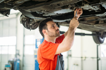 Auto mechanic working in garage. Repair service.