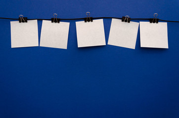 Five paper sheets attached with a binding clip on top of a blue background