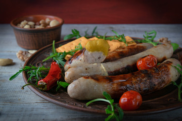 Fototapeta na wymiar brown dish with grilled sausages with mustard and arugula. on a wooden background