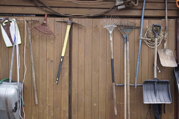 shovels rakes hammers hanging on wooden wall