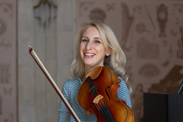 Young positive blonde playing violin