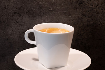 Eine Tasse cremiger Kaffee vor einer strukturierten Steinwand