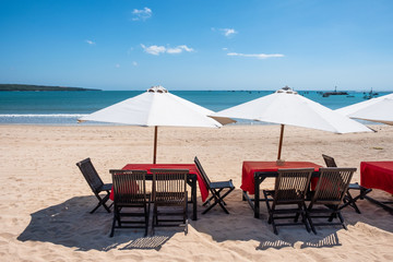 Red wooden dining table with white umbrella on the beach