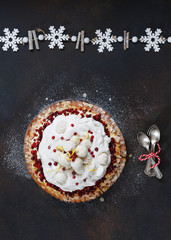 Obraz na płótnie Canvas Holiday cranberry lemon meringue pie with coconut snowballs on top and bunch of spoons beside. Top view, blank space, dark rustic background