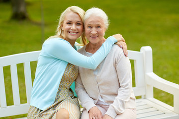 family, generation and people concept - happy smiling young daughter with senior mother sitting on...