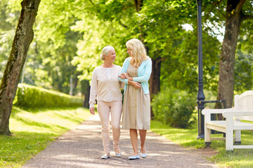 family, generation and people concept - happy smiling young daughter with senior mother walking at summer park