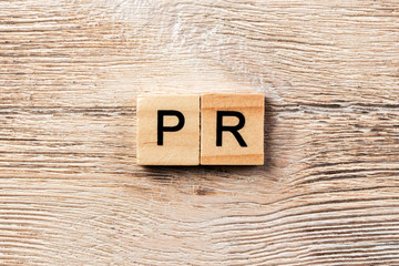 pr word written on wood block. public relation text on table, concept