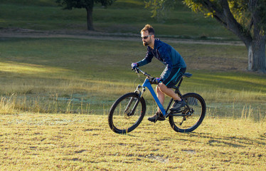 Obraz premium A cyclist rides the hills, Beautiful portrait of a guy on a blue bicycle