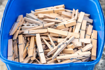 Many wooden clothes pegs in a blue plastic bucket