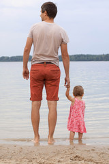 Father and daughter looking at beautiful lake.