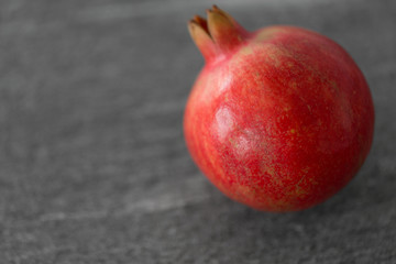 food, fruits and healthy eating concept - close up of pomegranate on stone table