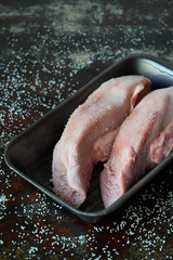 Pork tongue before cooking on black background. Raw meat. Offal