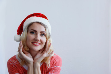Beautiful blonde girl in christmas hat thinks about christmas and smiling