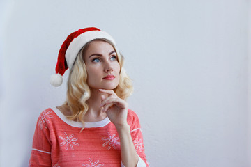 Beautiful blonde girl in christmas hat thinks about christmas