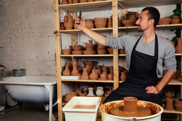 business man potter selfie photograph self portrait on smartphone works with clay on a pottery wheel in a creative workshop student of the Faculty of Art Sculptor