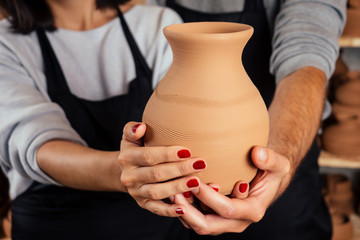 a pottery salesman and salewoman sells a clay vase pot close up in workshop