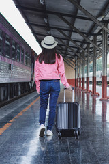 Fototapeta na wymiar Woman traveler tourist walking with luggage at train station. Active and travel lifestyle concept