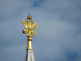 Coat of arms of Russia on cloudy sky. Golden Imperial eagle, Russian state emblem on top of the tower on Red square in Moscow