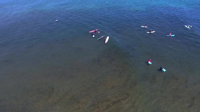 Flyover tilting down of surfers at a beach in California