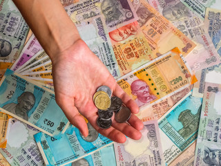 Woman's hands holding coins over 10, 20, 50, 100, 200, 500 and 2000 Indian rupees, old and new notes.