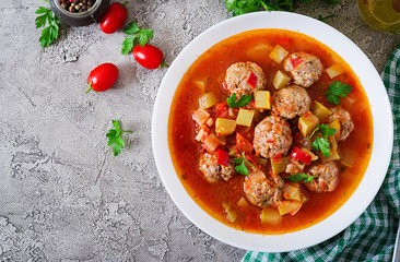 Hot stew tomato soup with meatballs and vegetables closeup in a bowl on the table. Albondigas soup, spanish and Mexican food. Top view. Flat lay