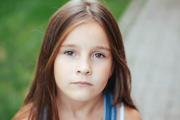 Fototapeta premium Model little beautiful girl with long hair, street fashion near the wall on a summer
