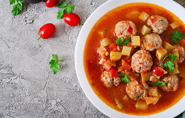 Hot stew tomato soup with meatballs and vegetables closeup in a bowl on the table. Albondigas soup, spanish and Mexican food. Top view. Flat lay