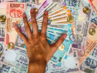 Hands over 10, 20, 50, 100, 200, 500 and 2000 Indian rupees, coins, old and new notes.