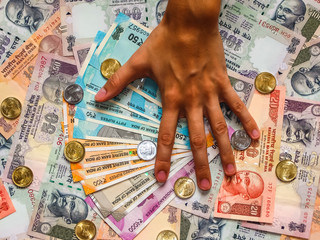 Hands over 10, 20, 50, 100, 200, 500 and 2000 Indian rupees, coins, old and new notes.
