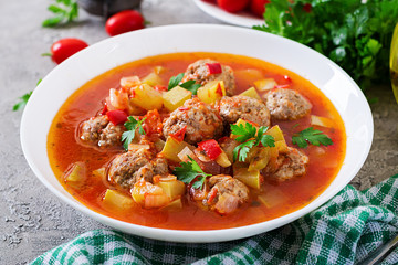 Hot stew tomato soup with meatballs and vegetables closeup in a bowl on the table. Albondigas soup,...
