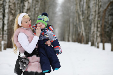 Young mother walks on a winter day with a baby in her arms in th